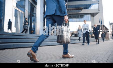 Close Up Leg Shot of a Businessman in a Suit Commuting to the Office on Foot. He's Carrying a Leather Case. Other Managers and Business People Walk Stock Photo