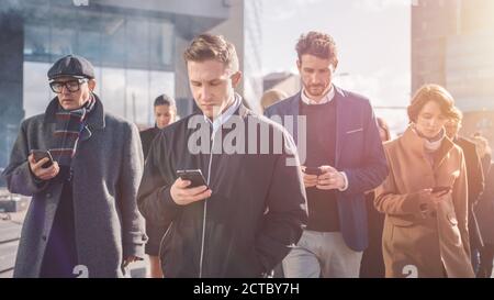 Office Managers and Businessmen are Walking in Front of Modern Glass Office Building and Use Their Smartphones. People are Dressed Smartly. They are Stock Photo