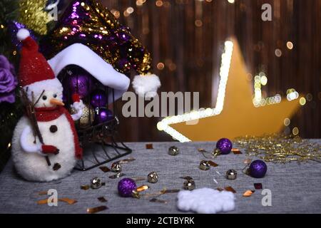 Toy snowman in a new year setting on a golden background with a glowing star Stock Photo