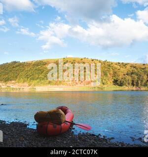 Orange packraft rubber boat with backpack on a river. Packrafting. Active lifestile concept Stock Photo