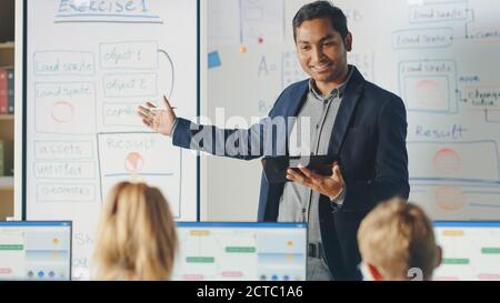 Elementary School Class: Teacher Uses Interactive Digital Whiteboard, Explains Lesson to Diverse Group of Smart Children. Kids getting Modern Stock Photo