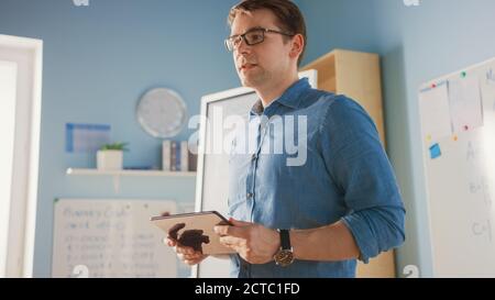 School Class: Portrait of the Enthusiastic and Motivated Teacher Using Digital Tablet Computer, Explains Lesson to Smart Children. Students Getting Stock Photo