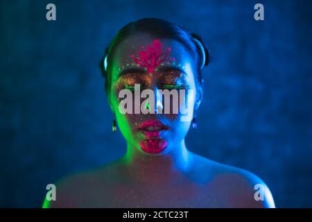 Portrait of painted woman in fluorescent powder and paint. Colorful, interesting and unusual shoot. Stock Photo