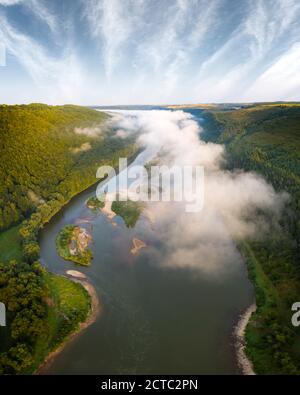 Flight through majestic foggy river and lush green forest at sunrise time. Landscape photography. Dnister, Ukraine, Europe Stock Photo