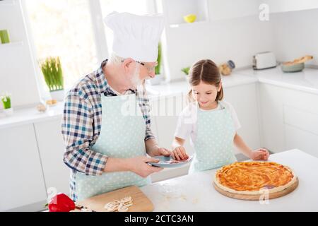Portrait of his he her she nice friendly cheerful focused grey-haired granddad grandchild cooking delicious dish pizza cookery healthy nutrition Stock Photo