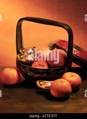 Chinese new year ornament, basket of mandarin oranges and gold ingots Stock Photo