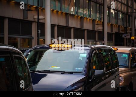 London, UK - February 2, 2020 - London black cabs lined up on sidewalk waiting for customers outside King's Cross station Stock Photo