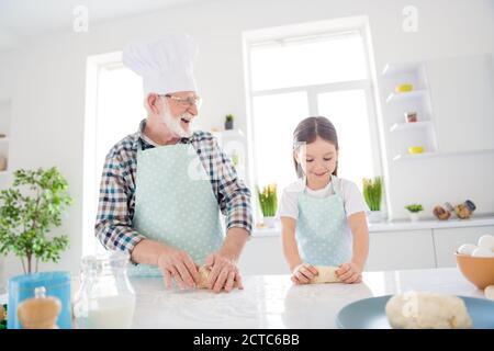 Portrait of nice cheerful cheery focused grey-haired grandpa grandchild making domestic tasty yummy dough baking cookies pie stay quarantine leisure Stock Photo