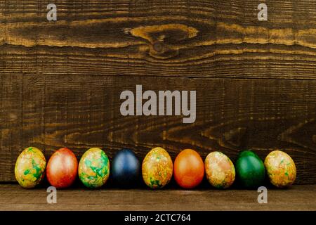 Easter eggs in a row on the dark brown wooden background, copy space Stock Photo