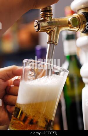 Hand of bartender pouring beer into glass Stock Photo