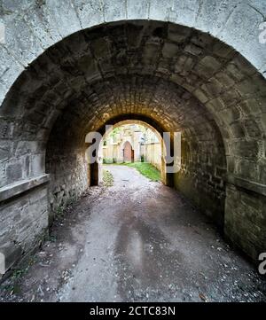 Dark passageway of roughly hewn stones with a round arch Stock Photo