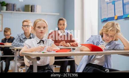 Elementary Classroom of Diverse Children Listening to the Teacher Giving a Lesson. Young Kids in School Learning Science, Creative Thinking Stock Photo