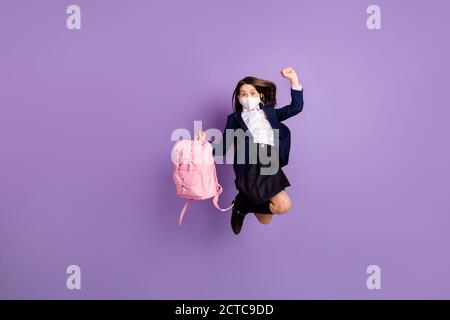 Full length body size view of nice carefree healthy small little long-haired girl win winner jumping having fun wearing safety mask isolated lilac Stock Photo