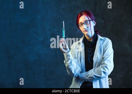 Red haired girl doctor shows syringe with vaccine. Virus protection concept with copy space. Stock Photo