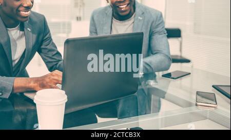 smiling colleagues looking at work on a laptop in the office. Stock Photo