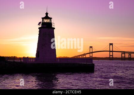Sunset over Newport Harbor Lighthouse with bridge and colorful sky Stock Photo