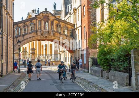 OXFORD CITY ENGLAND CYCLISTS AND PEOPLE IN NEW COLLEGE LANE WITH HERTFORD BRIDGE ALSO CALLED THE BRIDGE OF SIGHS Stock Photo