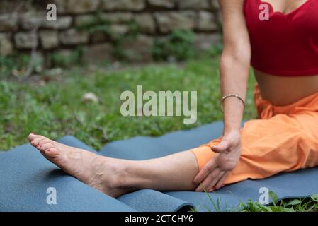 Athletic woman sitting in splits, Monkey yoga pose, asana Hanumanasana, stretching exercise. Part of the body. Foot in the focus. Stock Photo