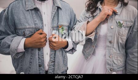 man and woman dressed in white wedding clothes denim blue jackets Stock Photo