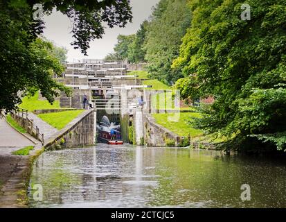 A canal longboat entering five-rise locks in light rain Stock Photo