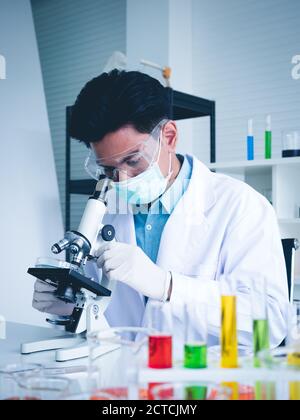 Asian male scientist Is working seriously Chemistry experiment With looking at the microscope In the laboratory, the color tone image. Stock Photo