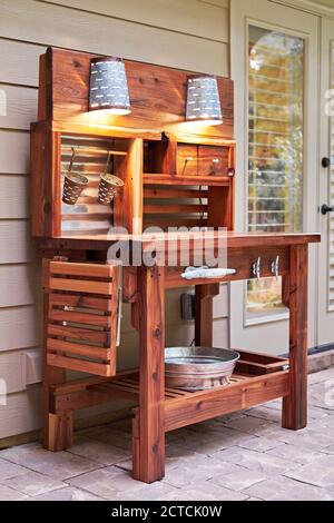 Home gardener cedar potting bench or table with lights on a patio. Stock Photo