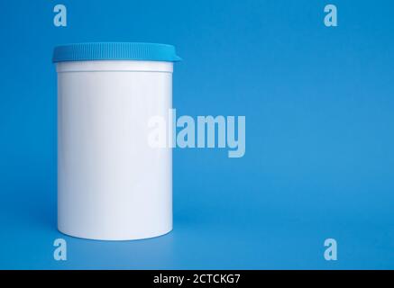 Pill dispenser can or jar. Single white large plastic container with blue screw top, reusable. Used to dispense and store supplements and medicine. Stock Photo