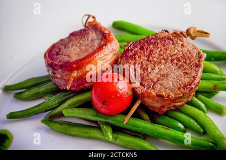 Grilled pork medallions on skewers with string beans and whole tomatoes. Ketogenic diet - high-fat nutrition. Paleo Diet. Pegan diet. Stock Photo