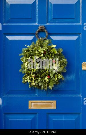 Detail of blue front door with Christmas garland wreath made from holly Stock Photo