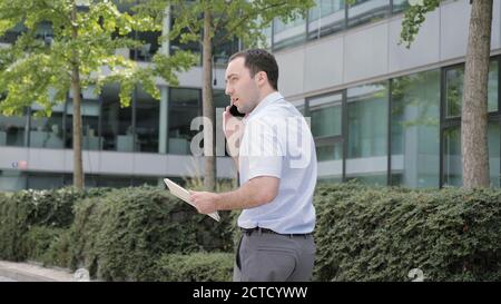 Man on Phone - young businessman walking using smartphone in sma Stock Photo