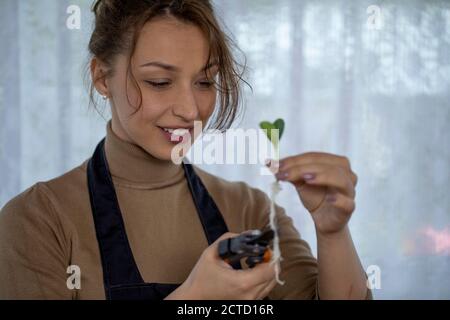 Portarit of lovely housewife holding flowers roots in his hands and smiling, Stock Photo
