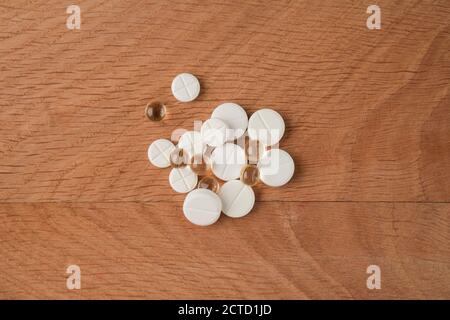 A bunch of various medicines, pills lying around without packaging, on a wooden board Stock Photo