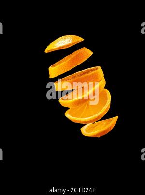 Falling orange and orange slices. Isolated on a black background. Stock Photo