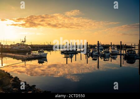Beautiful sunset with clouds over marina with boats in Bandon, Oregon Stock Photo