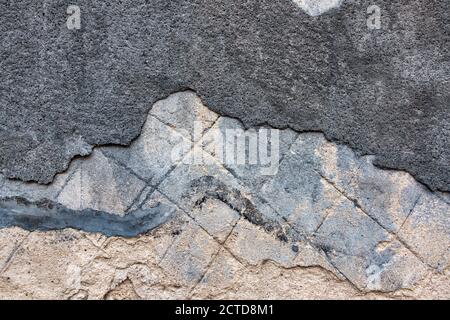 Old decrepit dirty plaster wall background with cracked structure. Old black gray grey mortar wall with rough shabby stucco peeled messy surface Stock Photo