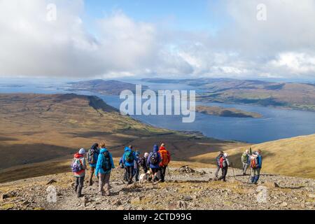 A walking group heading down from the Munro Ben More on the Island of Mull towards Loch na Keal Stock Photo