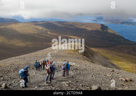 A walking group heading down from the Munro Ben More on the Island of Mull towards Loch na Keal Stock Photo