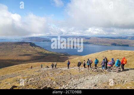 A walking group heading down from the Munro Ben More on the Island of Mull towards Loch na Keal Stock Photo