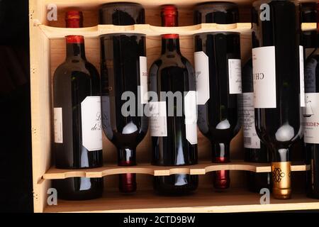Bottles of red wine lying flat in a wooden case. Stock Photo