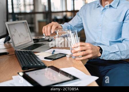 Stock trader drinking water and working in office Stock Photo