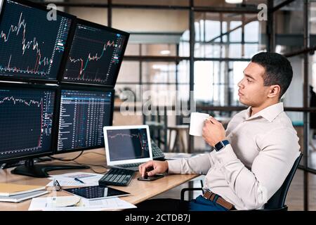 Stock trader analyzing stat and dynamic on forex charts and drinking coffee Stock Photo