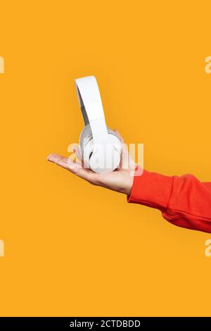 Freestyle. Mulatto guy in hoodie standing isolated on yellow with wireless headphones close-up Stock Photo