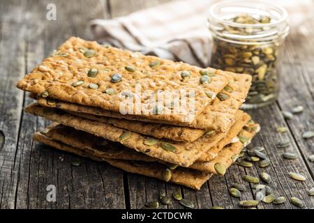 The  crispy bread with pumpkin seeds. Knackebrot on old wooden table. Stock Photo