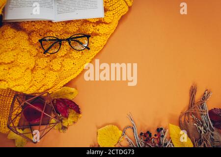 Autumn background with book, leaves, sweater, candle, scarf and glasses. Flat lay hygge composition. Space Stock Photo