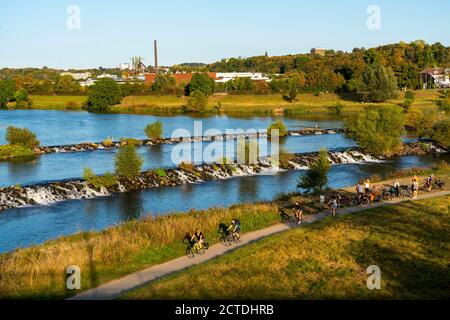 The Ruhrwehr, barrage of the Ruhr near Hattingen, cyclists, on the Ruhr valley cycle path, in the back the LWL industrial museum, former steelworks He Stock Photo