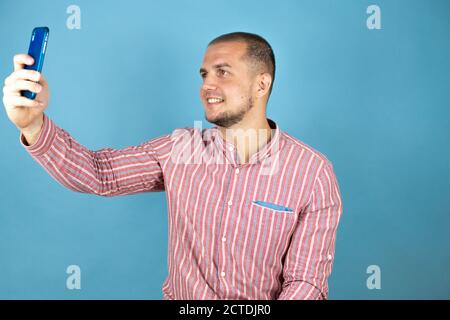 Russian business man over blue background taking himself a selfie. Stock Photo