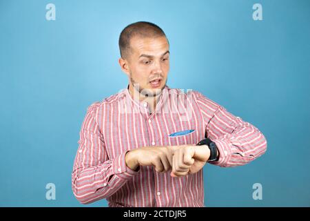 Russian business man over blue background surprised and pointing his watch because it's late Stock Photo