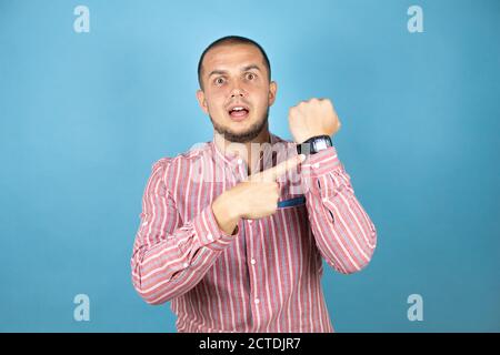 Russian business man over blue background showing his watch surprised Stock Photo