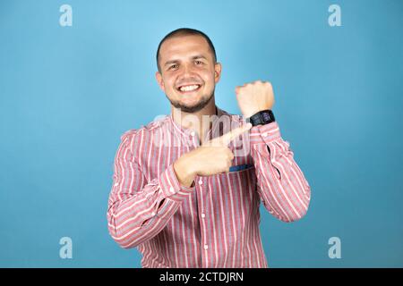 Russian business man over blue background surprised and pointing his watch because it's late Stock Photo