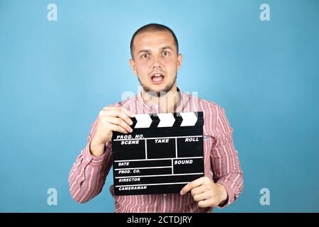 Russian business man over blue background holding clapperboard very happy having fun Stock Photo